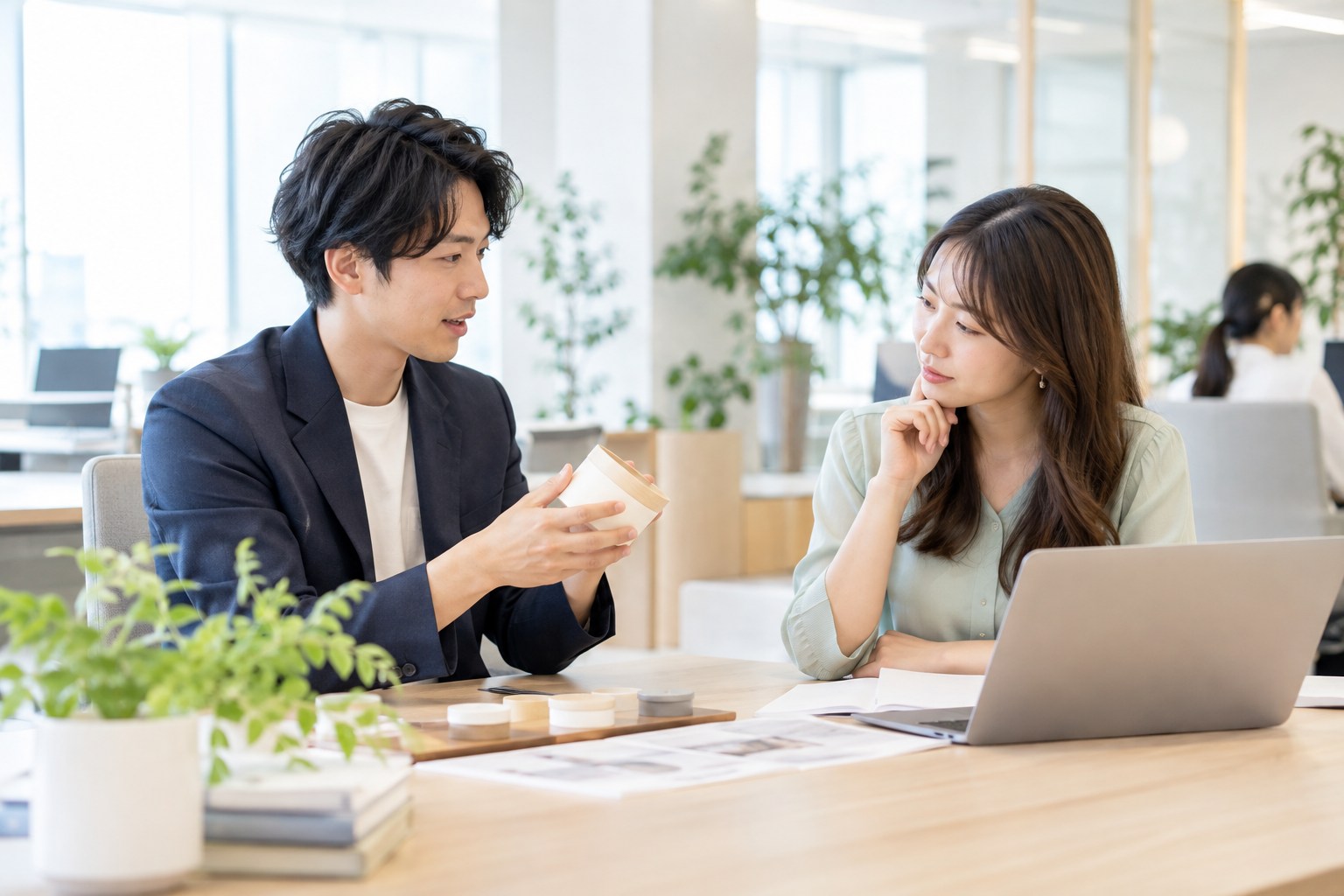 明るいオフィスで、製品のサンプルを見ながら説明する担当者