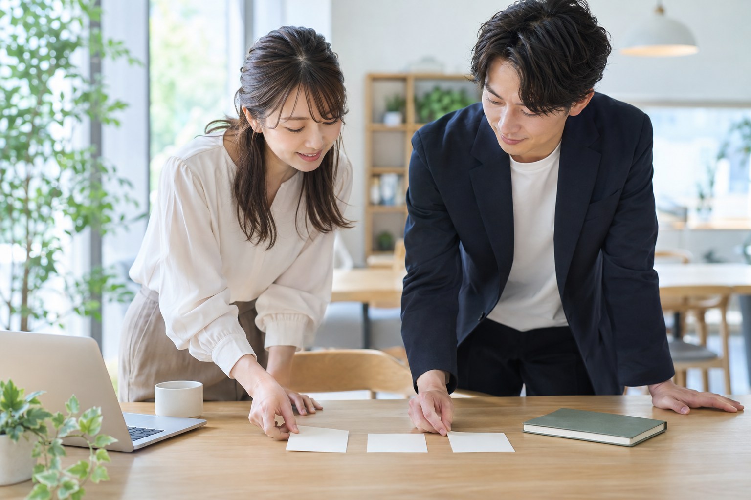 投稿に使う素材とノートを並べ、確認する内容を相談する二人
