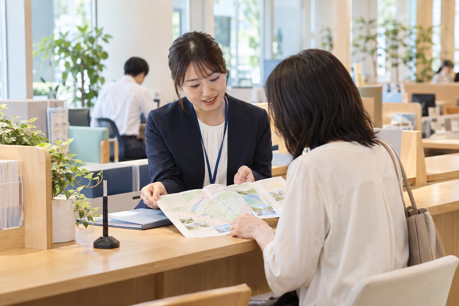 公共施設の窓口で地域の案内を確認する担当者と成人の来訪者