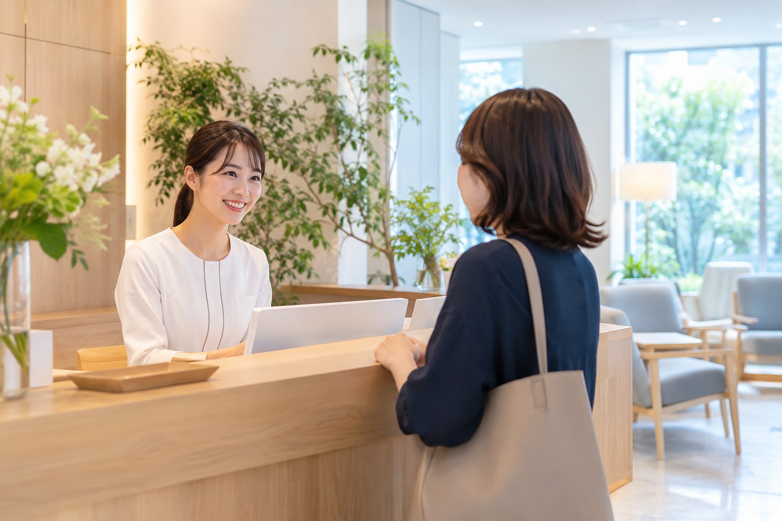 明るいクリニックの受付で成人の来訪者を迎えるスタッフ